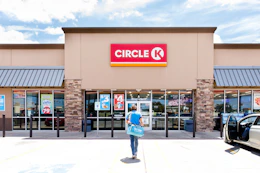 A person walking outside of a Circle K convenience store and gas station.