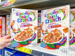 hand touching a box of cinnamon toast crunch cereal at dollar general