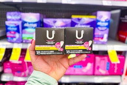 person holding 2 boxes of pantyliners