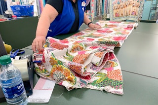 A Hobby Lobby employee cutting fabric.