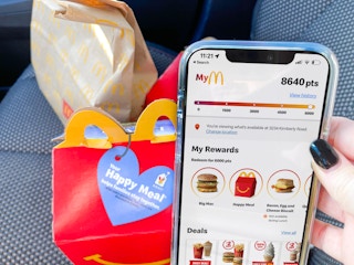 women holding cellphone with mcdonalds app next to happy meal