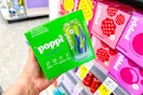 person holding a box of poppi soda by the shelf of poppi sodas