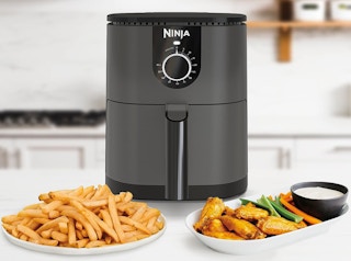 an air fryer next to plates of food