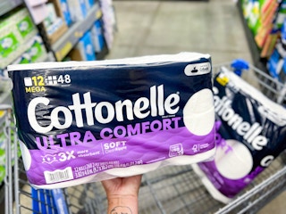 Someone putting some Cottonelle toilet paper into a cart in Walmart