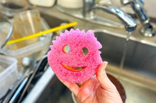 a person washing dishes with a scrub mommy 