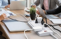 devices plugged into an power strip on a table 