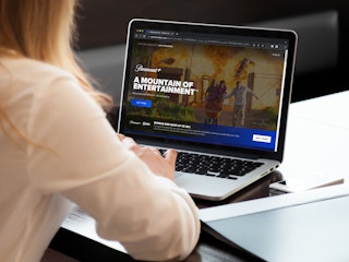 A woman looking at the Paramount Plus website on a laptop.