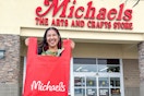 Woman holding out a shopping bag outside of a Michaels store