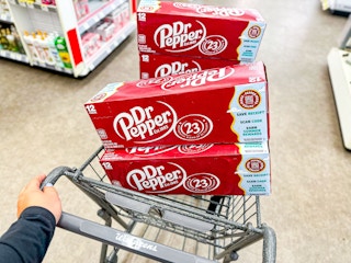 person pushing Walgreens cart with four Dr. Pepper 12-pack soda packs inside