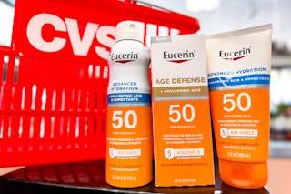 eucerin sunscreen spray and lotion in front of a red cvs basket