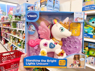 hand holding the Vtech Unicorn in front of a toy shelf at Target