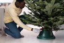 A man putting a Christmas tree into a tree stand.