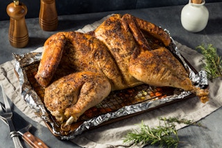 A spatchcocked turkey in a pan on a table.