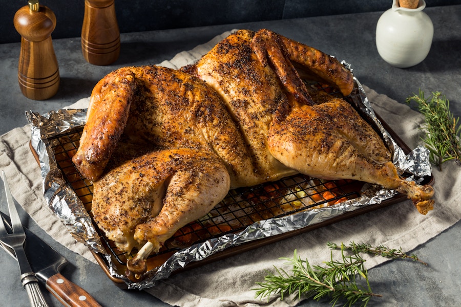 A spatchcocked turkey in a pan on a table.