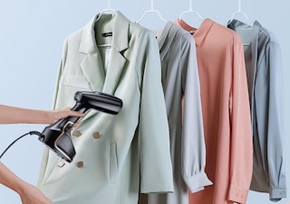 a garment steamer steaming a rack of clothes