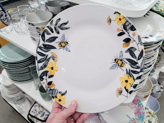 hand holding a plate with a bee design with flowers