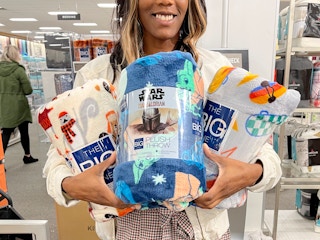A woman holding three throw blankets in her arms