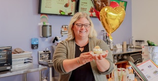 a person holding up a birthday treat inside of edible arrangements