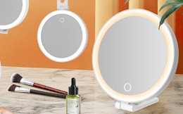 lighted mirrors next to makeup brush and a skincare bottle