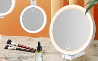 lighted mirrors next to makeup brush and a skincare bottle