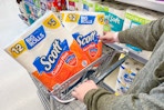 person pushing shopping cart with scott toilet paper