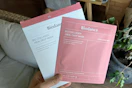 a hand holding a sheet mask in pink and white packaging
