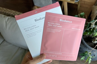 a hand holding a sheet mask in pink and white packaging