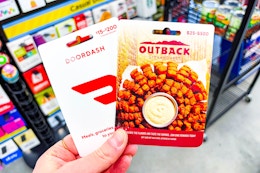hand holding doordash and outback gift cards