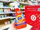 hand holding a bottle of tide stain remover in front of a target cart