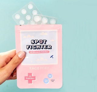A hand holding a package of Facetory Acne Spot Fighter.