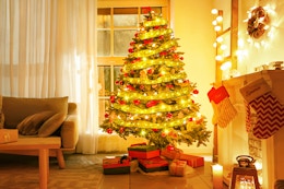 A Christmas tree wrapped in warm white LED ribbon stands in a festive living room.