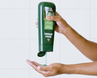 a person pouring body wash from a bottle into their hands
