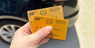 Someone holding two AAA Membership cards in front of a car