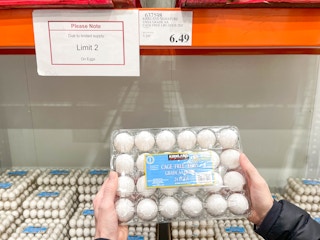 a person holding up eggs in costco