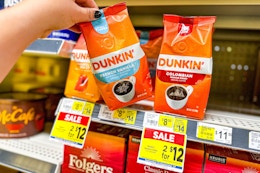 hand picking up a bag of dunkin' coffee
