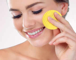 a woman using a cleansing pad on her face 