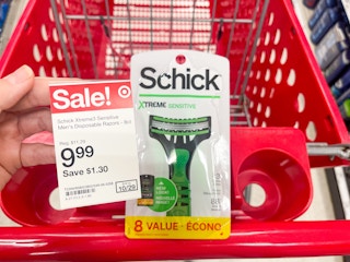 A sale sticker held out in front of a Schick Extreme Sensitive razor package sitting in a shopping cart.