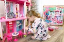 a little girl playing with the barbie dreamhouse 