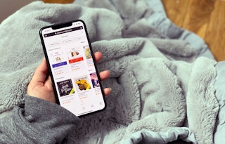 A hand holding a phone with Audible on the screen.