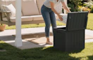 a person putting an item in a storage box on a patio
