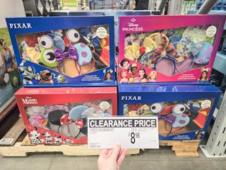 person holding a clearance sign for $8.98 in front of sets of disney ears