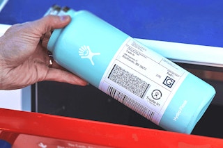 hand placing old hydro flask water bottle with label into mailbox