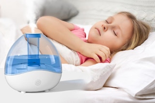 a girl asleep in a bed with a humidifier by her