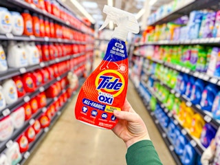 Tide Ultra Oxi Stain Remover Spray held up in center aisle in Walmart store