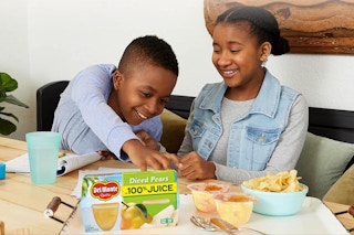 Children reaching for Del Monte Fruit Cup Snacks on table