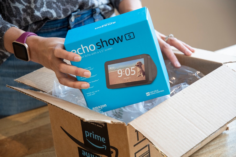 A person taking an Amazon Echo Show 5 out of an Amazon delivery box.