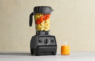 a blender on a table with a glass of juice