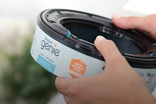 A hand holding a Diaper Genie pail refill
