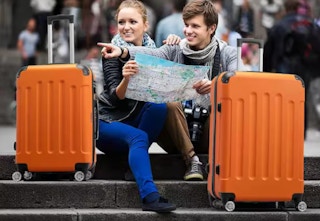 orange luggage pieces on steps with a couple of tourists