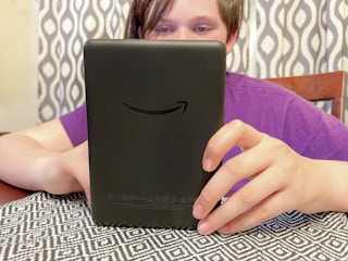 a teen reading on a kindle at the table